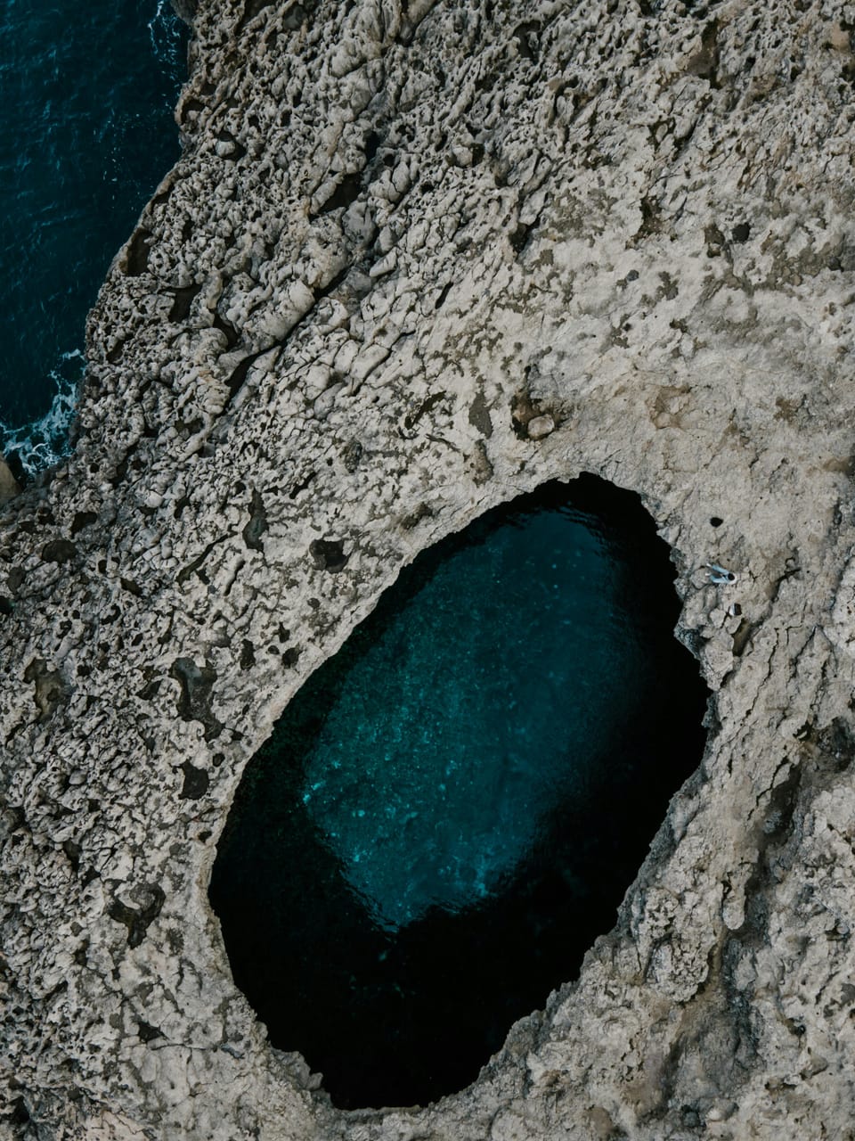 Hole in the rocks seen from above in Malta, with the sea in the middl